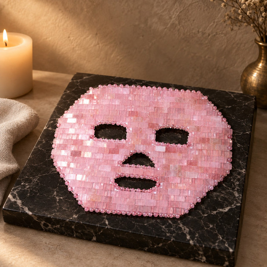 Masque de visage en mosaïque de quartz rose, posé sur un présentoir en marbre noir