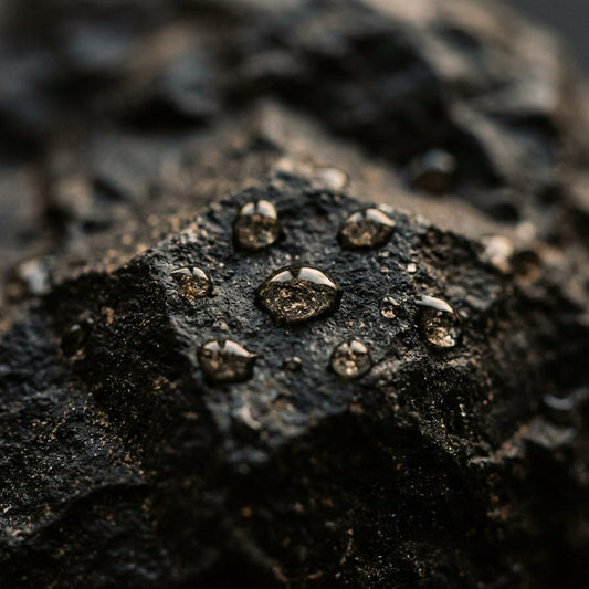 Des gouttes d'eau perlant sur une roche noire