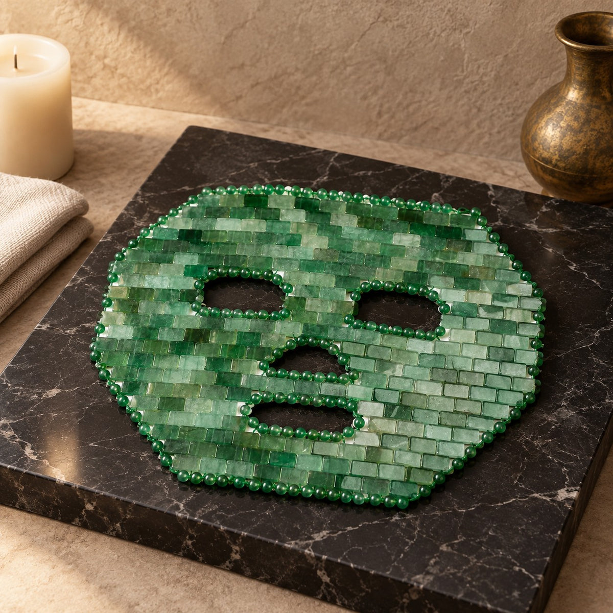 Masque de visage en mosaïque d’aventurine verte, posé sur un présentoir en marbre noir