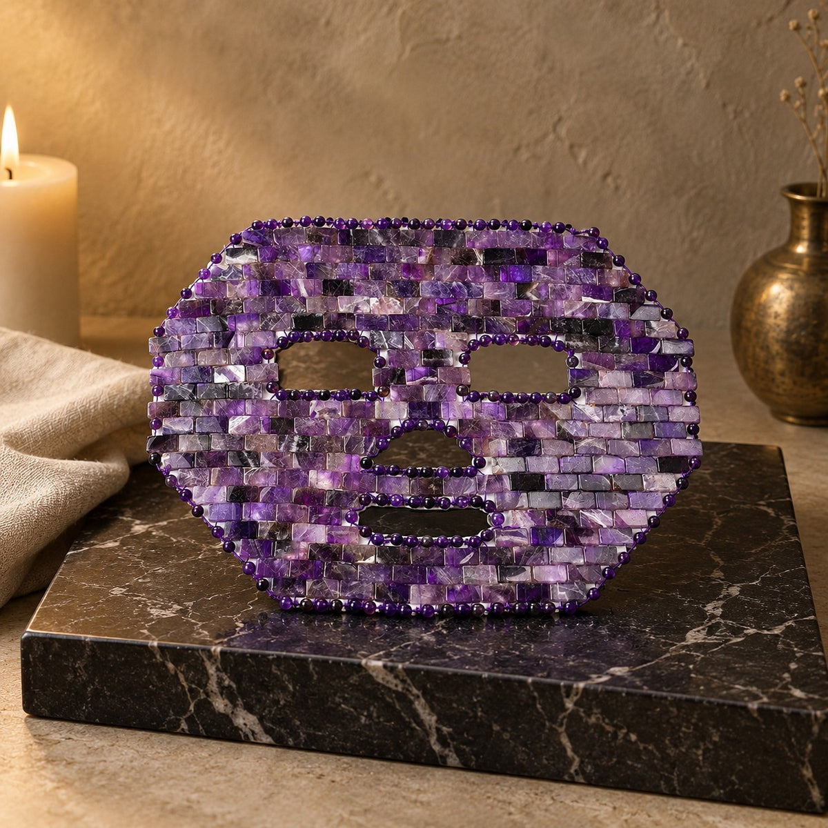 Masque de visage en mosaïque d’améthyste, posé sur un présentoir en marbre noir